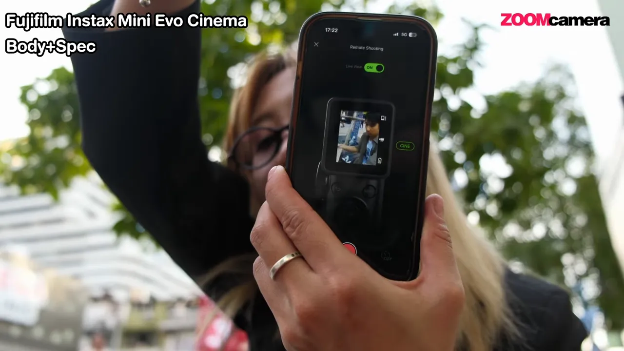 รีวิว FUJIFILM Instax mini Evo Cinema : กล้อง Hybrid ที่พาเราย้อนเวลาได้ 5 หน้าจอแอป Mini Evo แสดง Live View เป็น ON มีภาพตัวอย่างจากกล้องและปุ่มบันทึก พร้อมกล้อง Instax ถืออยู่ด้านข้าง