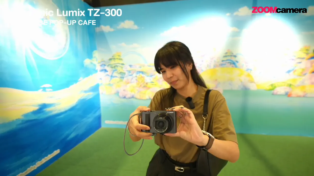 ผู้รีวิวยืนถือ Panasonic Lumix TZ-300 ถ่ายภาพต่อหน้าในบูธ One Piece Pop-Up Cafe